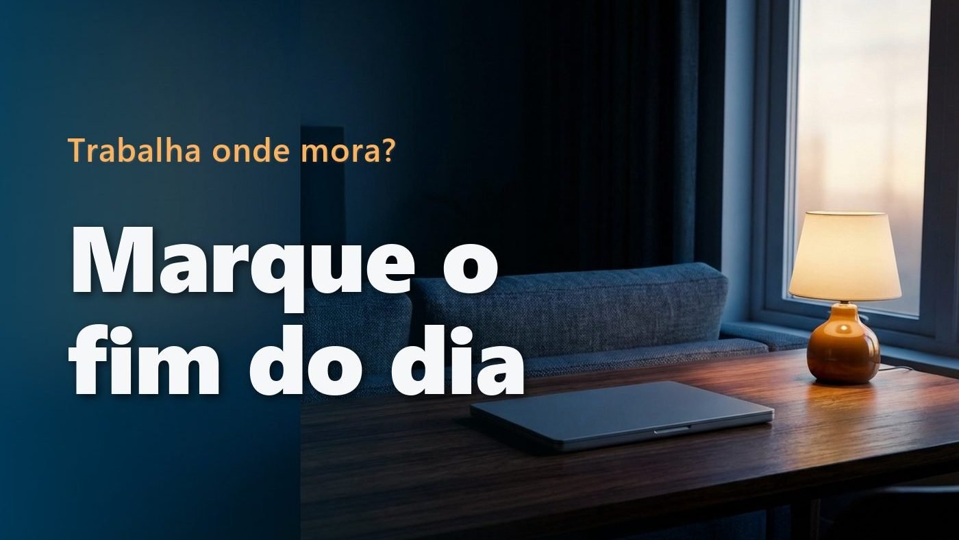 Notebook fechado sobre uma mesa de madeira ao entardecer, com um sofá e uma luminária acesa ao fundo