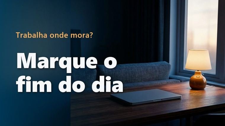 Notebook fechado sobre uma mesa de madeira ao entardecer, com um sofá e uma luminária acesa ao fundo
